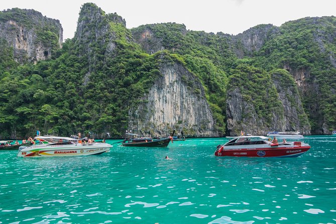 Limestone cliffs and longtail boats over jade water at Phi Phi